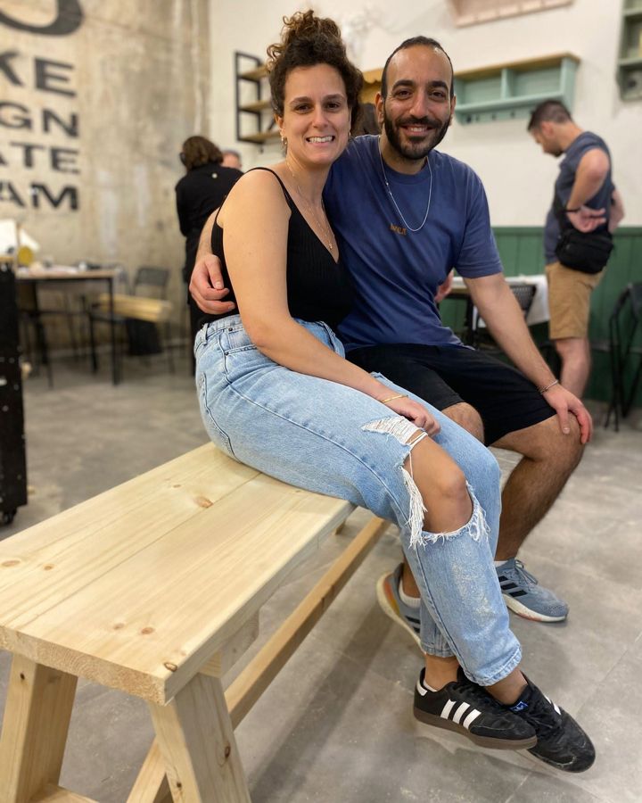 זוג יושב על ספסל עץ שבנה בסדנא